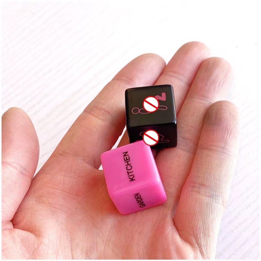 A pair of black and pink erotic dice with engraved action words and body parts, designed for spontaneous couples' play.