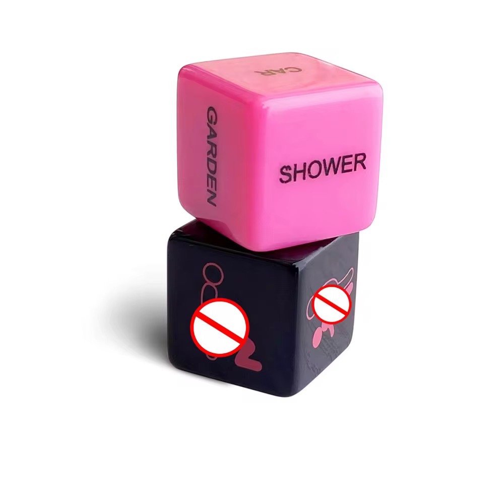 A pair of black and pink erotic dice with engraved action words and body parts, designed for spontaneous couples' play.