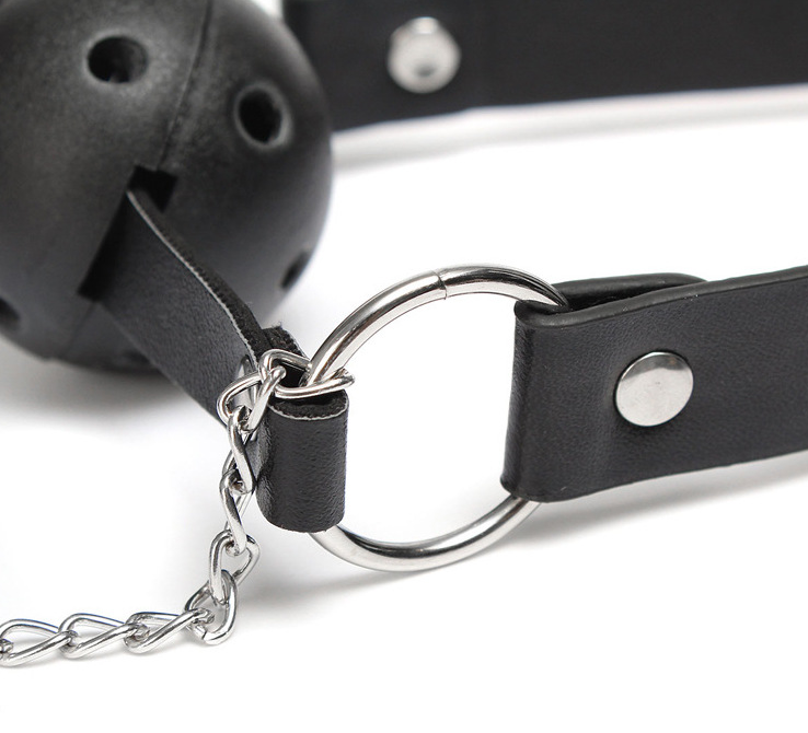 A classic black solid ball gag with an adjustable faux-leather strap and two integrated metal alligator nipple clamps on silver chains.