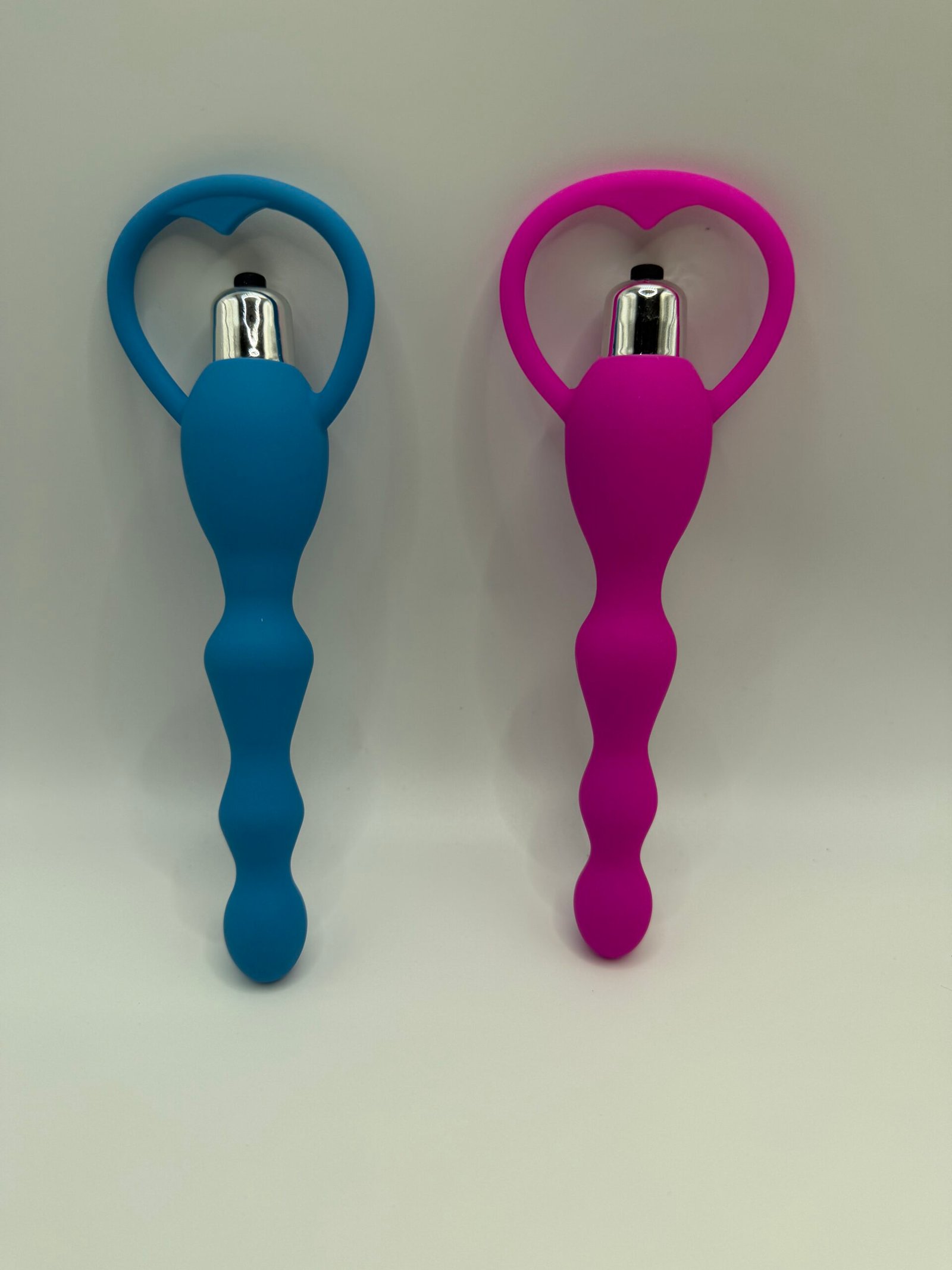 Ergonomically curved vibrating prostate plug with a flared safety base in pink and blue